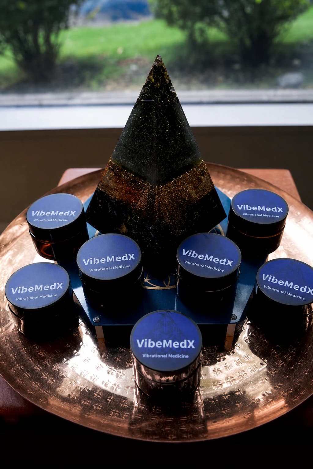 Finished VibeMedX shilajit resin jars arranged around an orgone pyramid